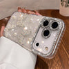 Clear glitter butterfly iPhone case with raised rhinestone camera frame on a table.