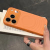 Orange water ripple MagSafe silicone iPhone case shown in hand with raised camera protection.