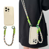 Cream iPhone case with patterned crossbody strap styled on a black outfit.