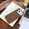 Brown braided iPhone case resting on a book and laptop with a slim, form-fitting profile