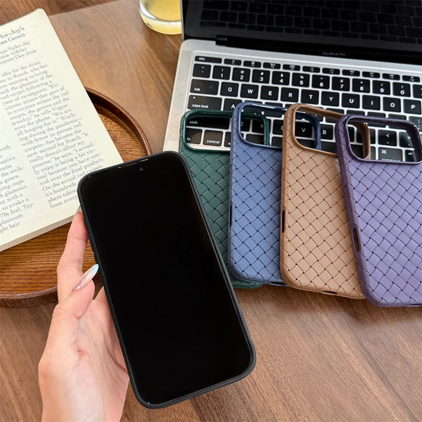 Four braided iPhone cases in green, blue, brown, and purple beside a laptop on a wooden table