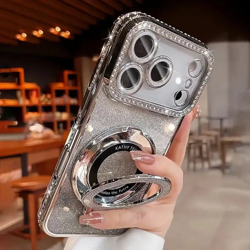 Clear glitter iPhone case with metallic edging and built-in holder, shown on a hand