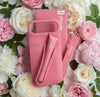 Pink phone case with 'rhode' branding held by a hand on a white background