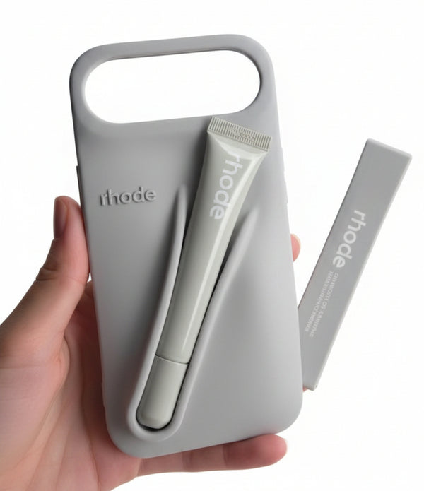 Hand holding a gray phone case with a cutout design, branded 'rhode', on a light surface.